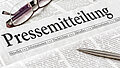 Zeitung mit der Überschrift Pressemitteilung mit brille und kuli
