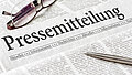 Zeitung mit der Überschrift Pressemitteilung mit brille und kuli