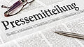 Zeitung mit der Überschrift Pressemitteilung mit brille und kuli