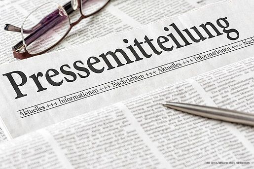 Zeitung mit der Überschrift Pressemitteilung mit brille und kuli