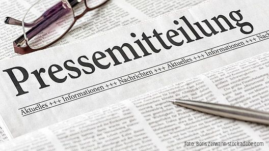 Zeitung mit der Überschrift Pressemitteilung mit brille und kuli