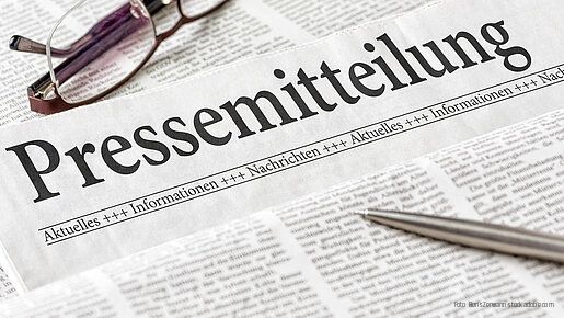 Zeitung mit der Überschrift Pressemitteilung mit brille und kuli