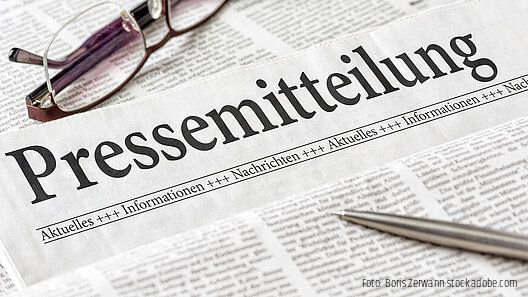 Zeitung mit der Überschrift Pressemitteilung mit brille und kuli