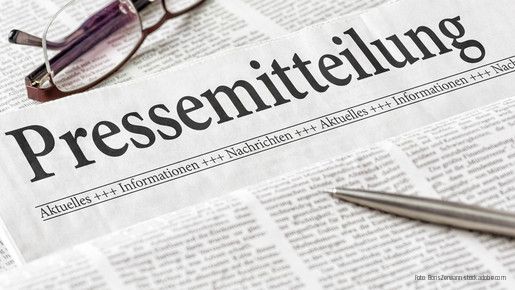 Zeitung mit der Überschrift Pressemitteilung mit Brille und Kuli