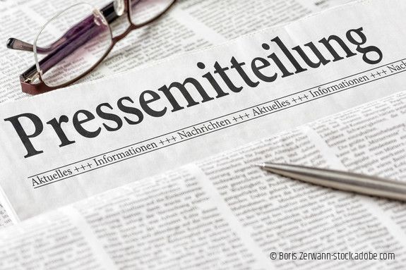 Zeitung mit der Überschrift Pressemitteilung mit brille und kuli