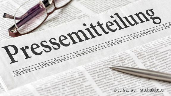 Zeitung mit der Überschrift Pressemitteilung mit Brille und Kuli